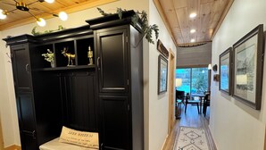 A hallway with a black wooden bench, a rug, and framed pictures on the walls. -  Newly remodeled-Lakefront cabin on 4th Lake w/dock & kayaks. Trail 5 Access (Old Forge)