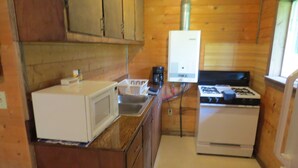 Une cuisine de taille réduite, dotée de meubles en bois, d’un four à micro-ondes, d’une cuisinière et d’un évier.
