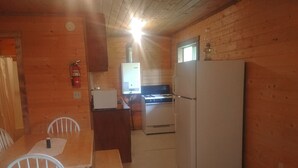 Une cuisine compacte équipée d’un réfrigérateur, d’une cuisinière et d’une petite table à manger avec des chaises.