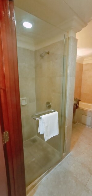 A glass-enclosed shower with a white towel hanging on the door handle.