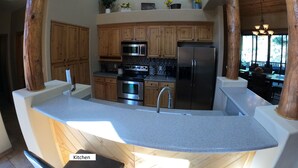 Una cocina con armarios de madera, electrodomésticos de acero inoxidable y encimera de granito.