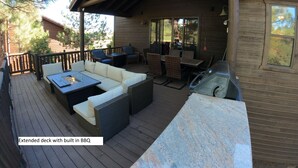 Una terraza amplia con una barbacoa integrada, mobiliario de mimbre y una encimera de piedra.