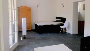 Une chambre à coucher avec un lit, une chaise, une armoire et une grande fenêtre.