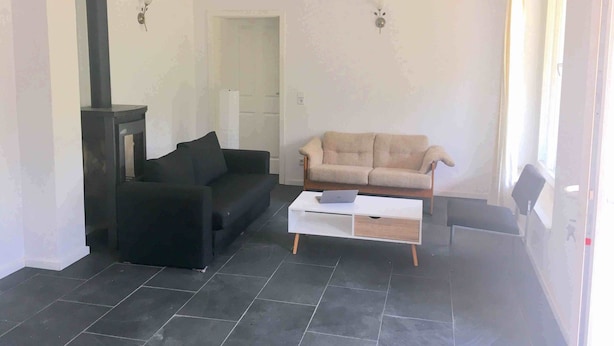 Un salon avec un canapé noir, un canapé beige et une table basse blanche.