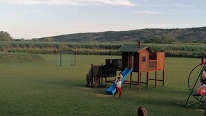 A playground with a slide and climbing structures in a grassy field. - Rajana bungalow 2(Olive House) (Ulcinj)