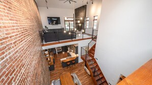 Ein mehrgeschossiges Interieur mit freigelegten Backsteinwänden, einer Treppe und einem Küchenbereich.