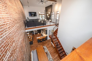 A multi-level interior with exposed brick walls, a staircase, and a kitchen area.