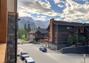 A two-story house with a stone facade, a garage, and a driveway with parked cars.