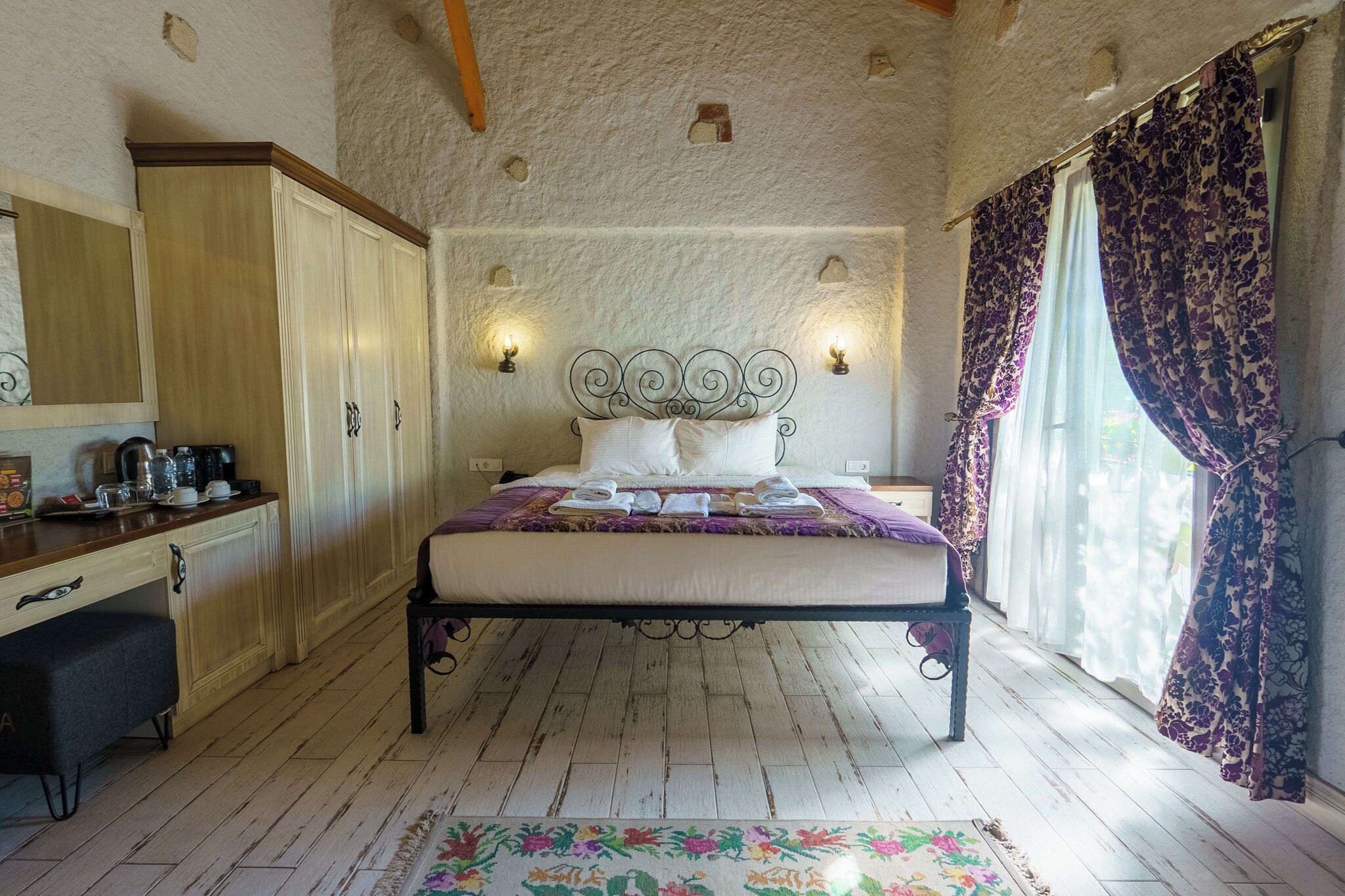 A bedroom with a bed, a desk, and a wardrobe.