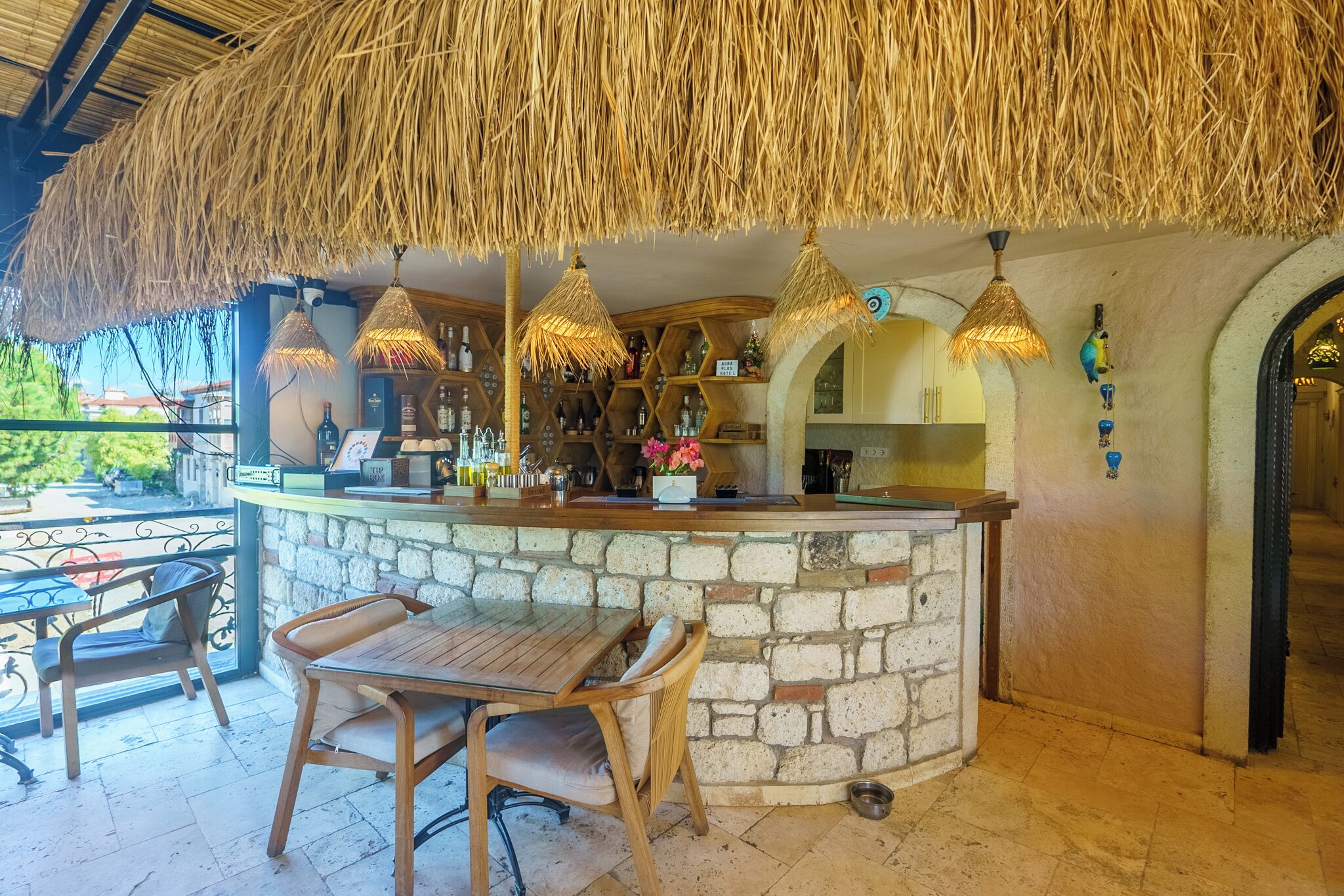 Una zona de bar con barra de piedra, sillas de madera y lámparas de techo de paja.