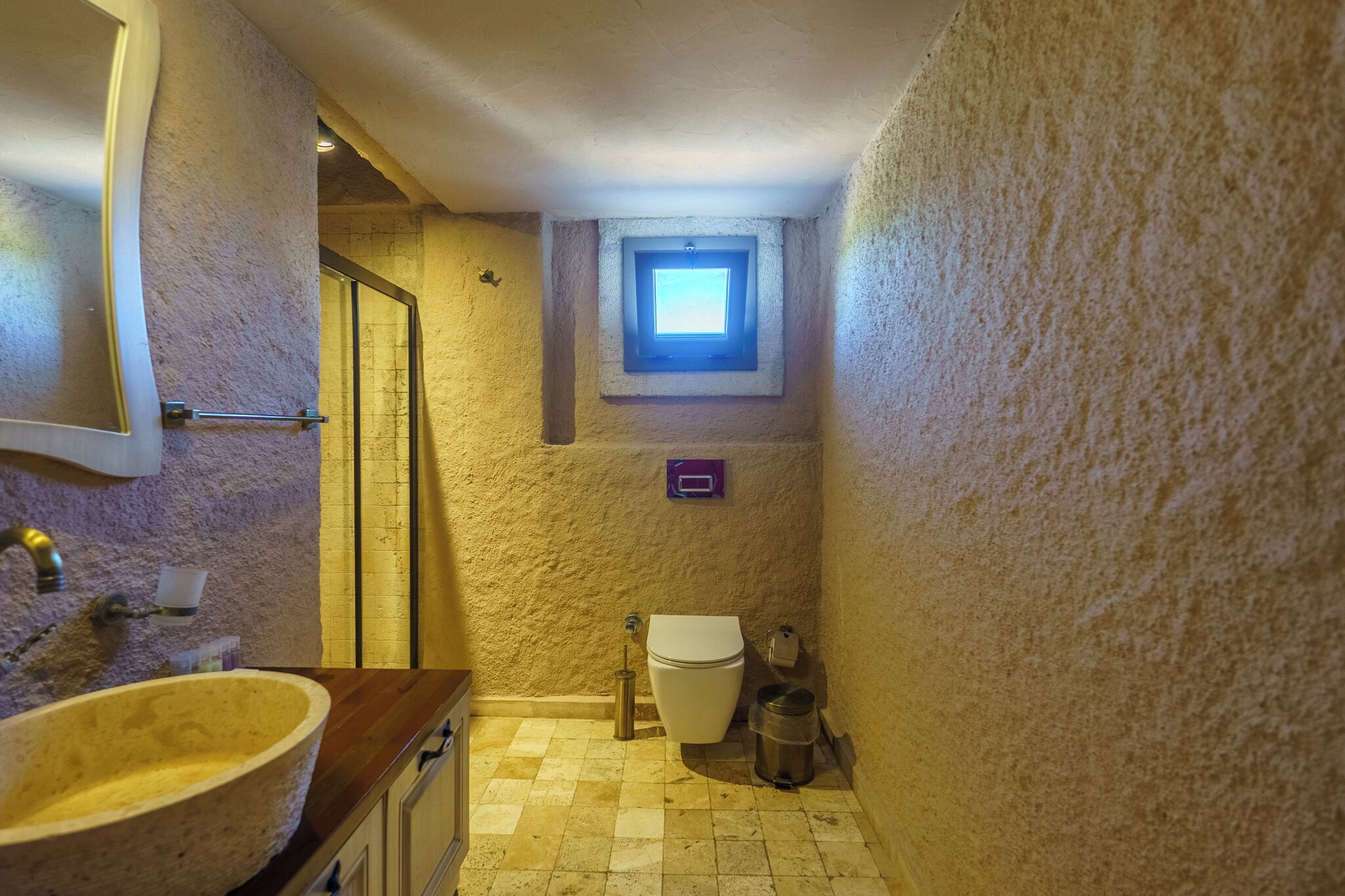 Une petite salle de bain avec un lavabo en pierre, des toilettes et une lucarne.
