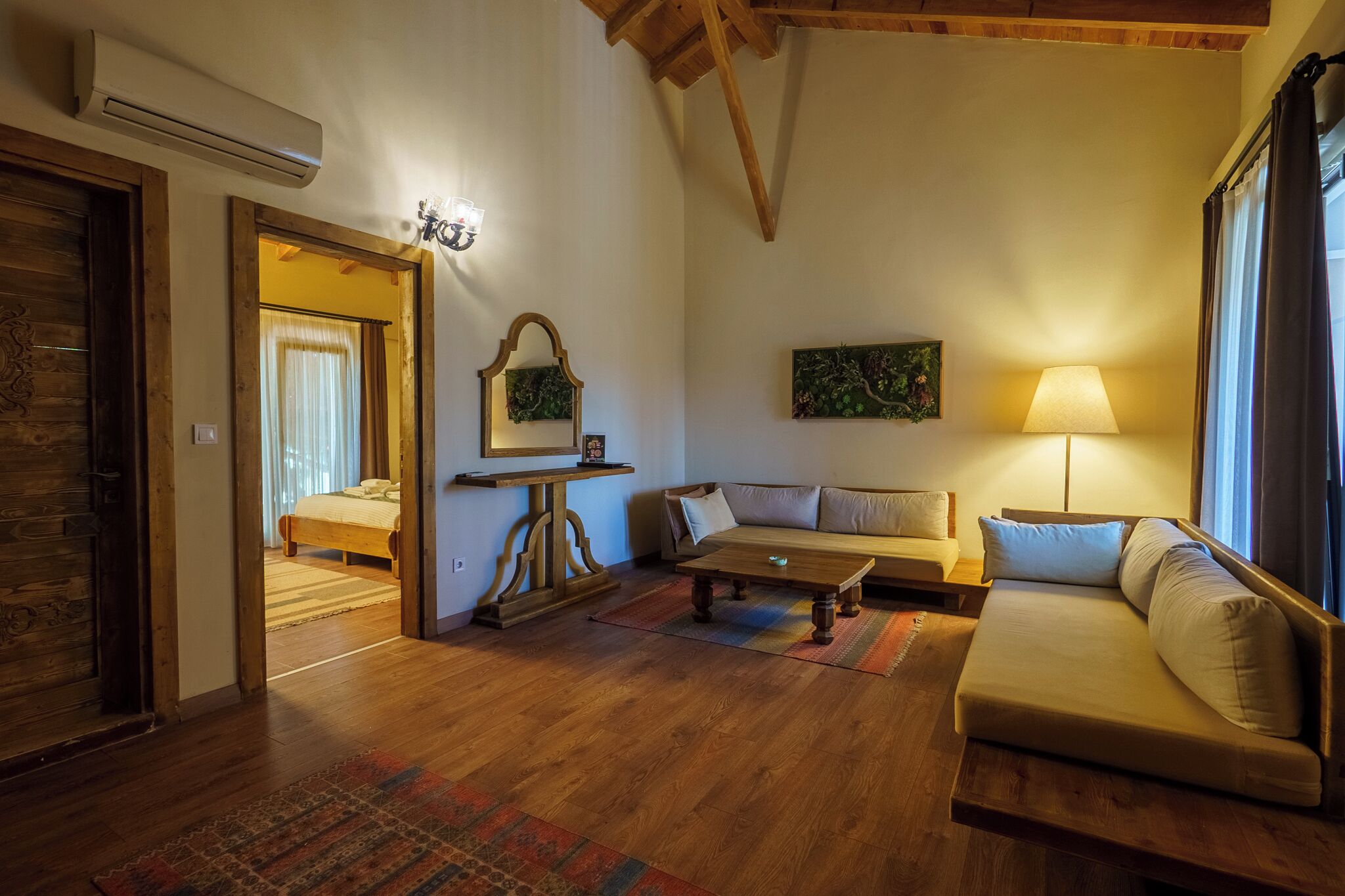 Una sala de estar acogedora con un sofá, una mesa de centro y una lámpara. Hay una puerta de madera y un espejo en la pared.