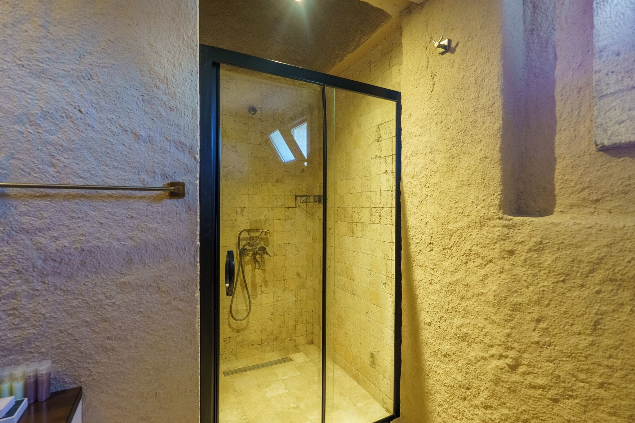 Une douche fermée par des parois en verre, avec un mur carrelé et un porte-serviettes.