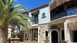 A hotel named 'AURA' with stone facade, large windows, and a balcony with decorative metalwork. - Alacati Aura Plus (Cesme)