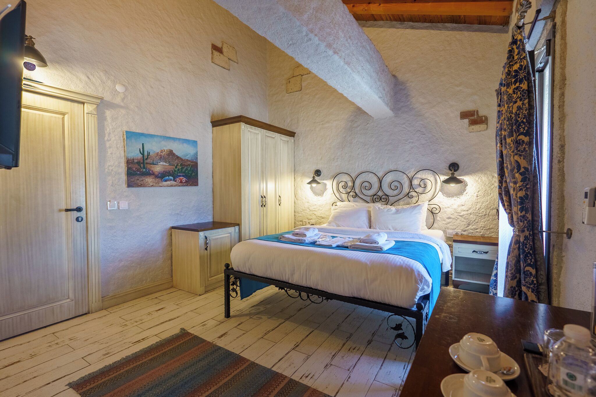 A bedroom with a bed, bedside table, lamp, and a painting on the wall.