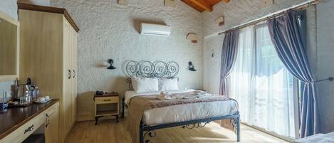 A bedroom with a wooden ceiling, a bed with a metal frame, a bedside table, a nightstand, and a window with curtains.