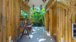 A wooden corridor with a table and lanterns, leading to a lush green garden. - Alacati Aura Plus (Cesme)