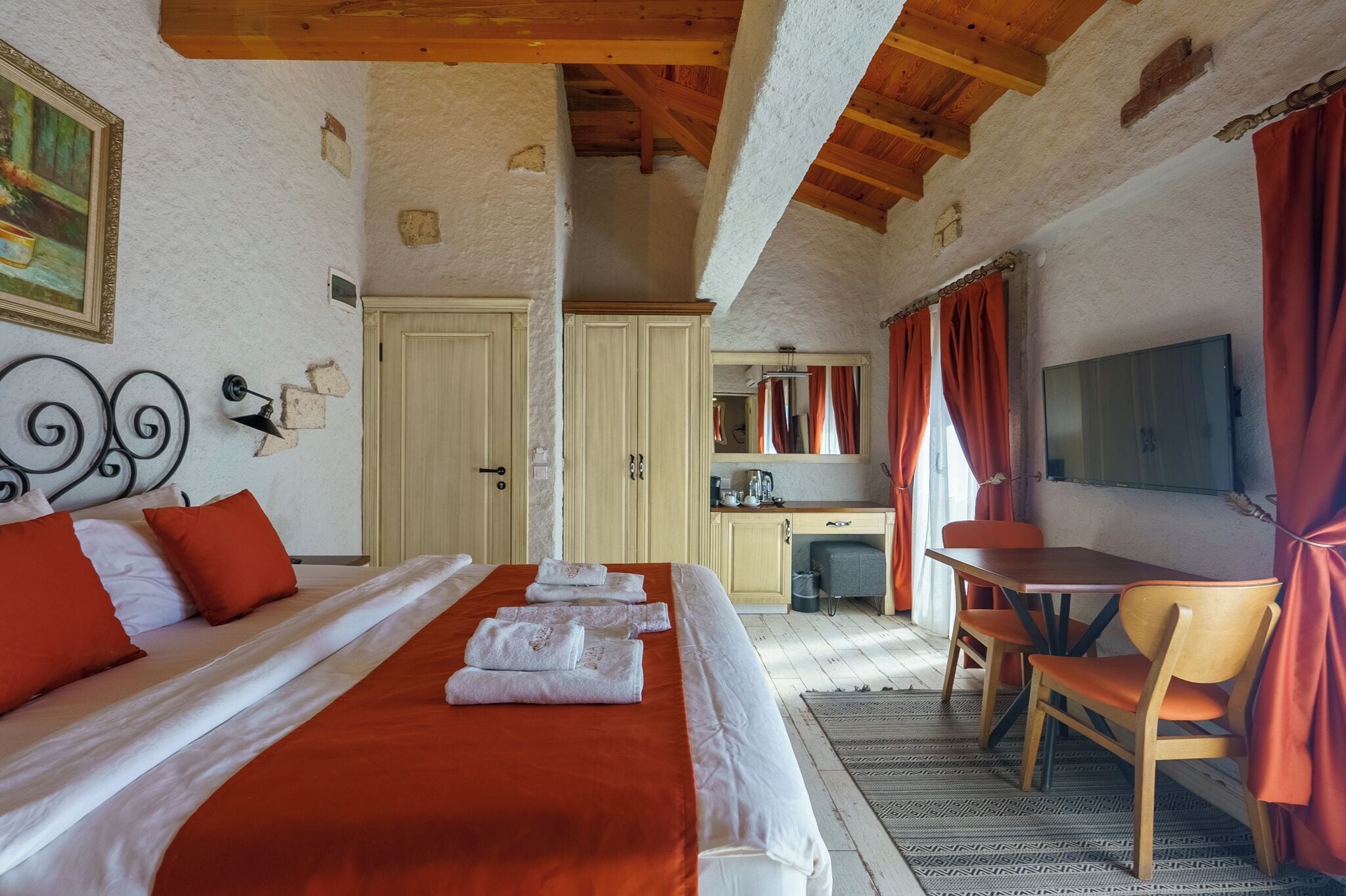 A bedroom with a bed, a desk, and a TV.