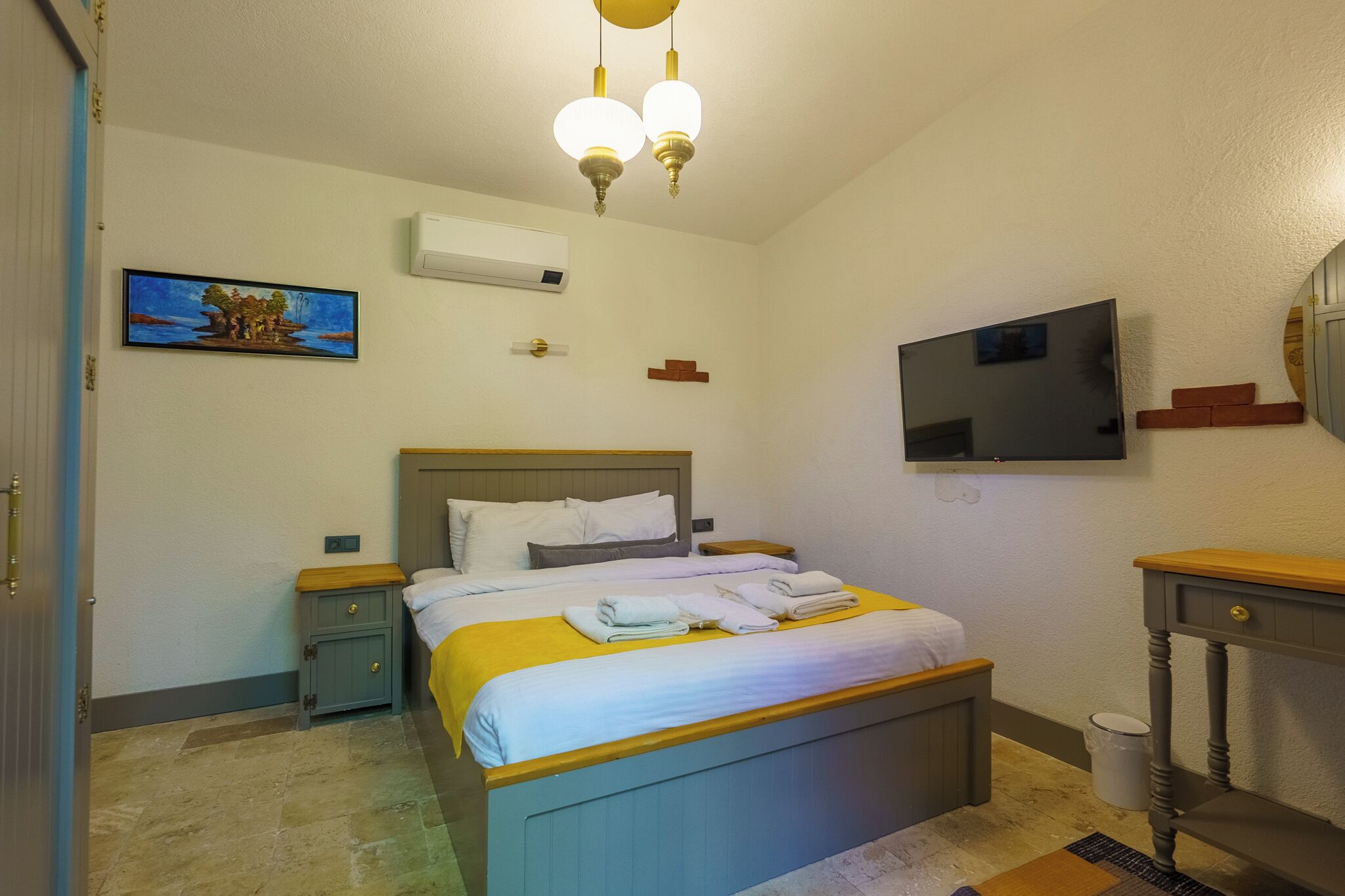 Una habitación de hotel con una cama, mesitas de noche, un televisor y un cuadro en la pared.