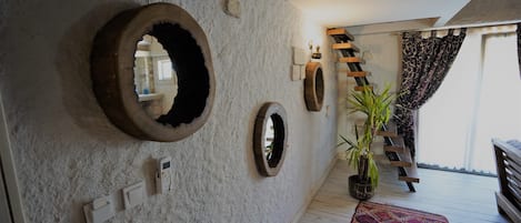 A hallway with circular wall decorations, a wooden staircase, and a potted plant.