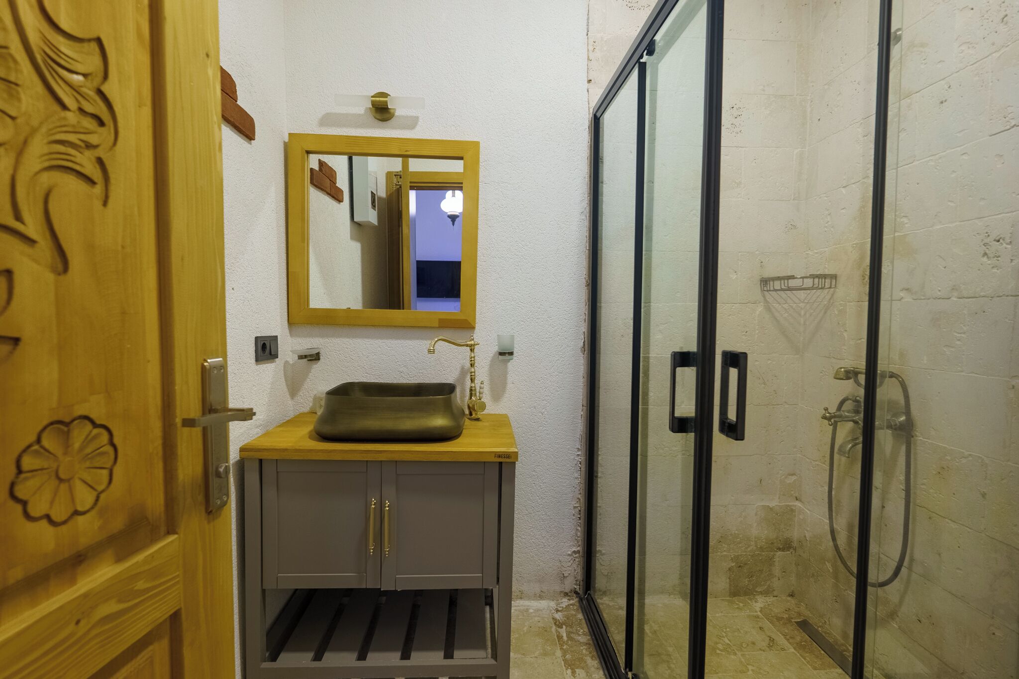 Un baño con tocador de madera, espejo y cabina de ducha de vidrio.
