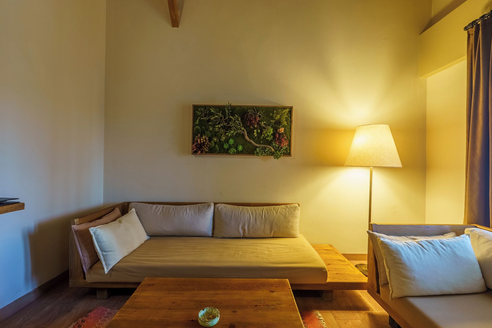 Een gezellige kamer met een bank, een houten bijzettafeltje en een lamp.