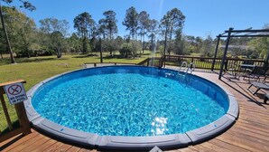 Una piscina elevada circular con un deck de madera alrededor.