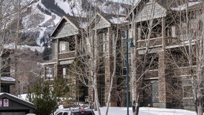 A historic building with a stone facade, multiple balconies, and a view of snow-covered mountains.