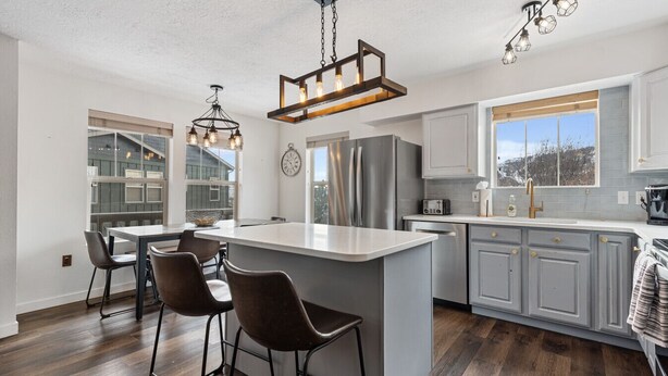 A modern kitchen with a large island, stainless steel appliances, and bar stools.