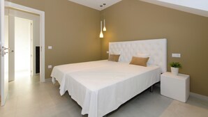 Een slaapkamer met een groot bed, een nachtkastje en een potplant.