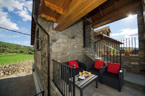 A stone building with a balcony, outdoor seating, and a staircase.