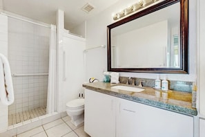 Une salle de bain équipée d’une douche, de toilettes, d’un lavabo et d’un grand miroir.