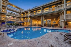 A hotel with a swimming pool, multiple balconies, and outdoor seating areas.