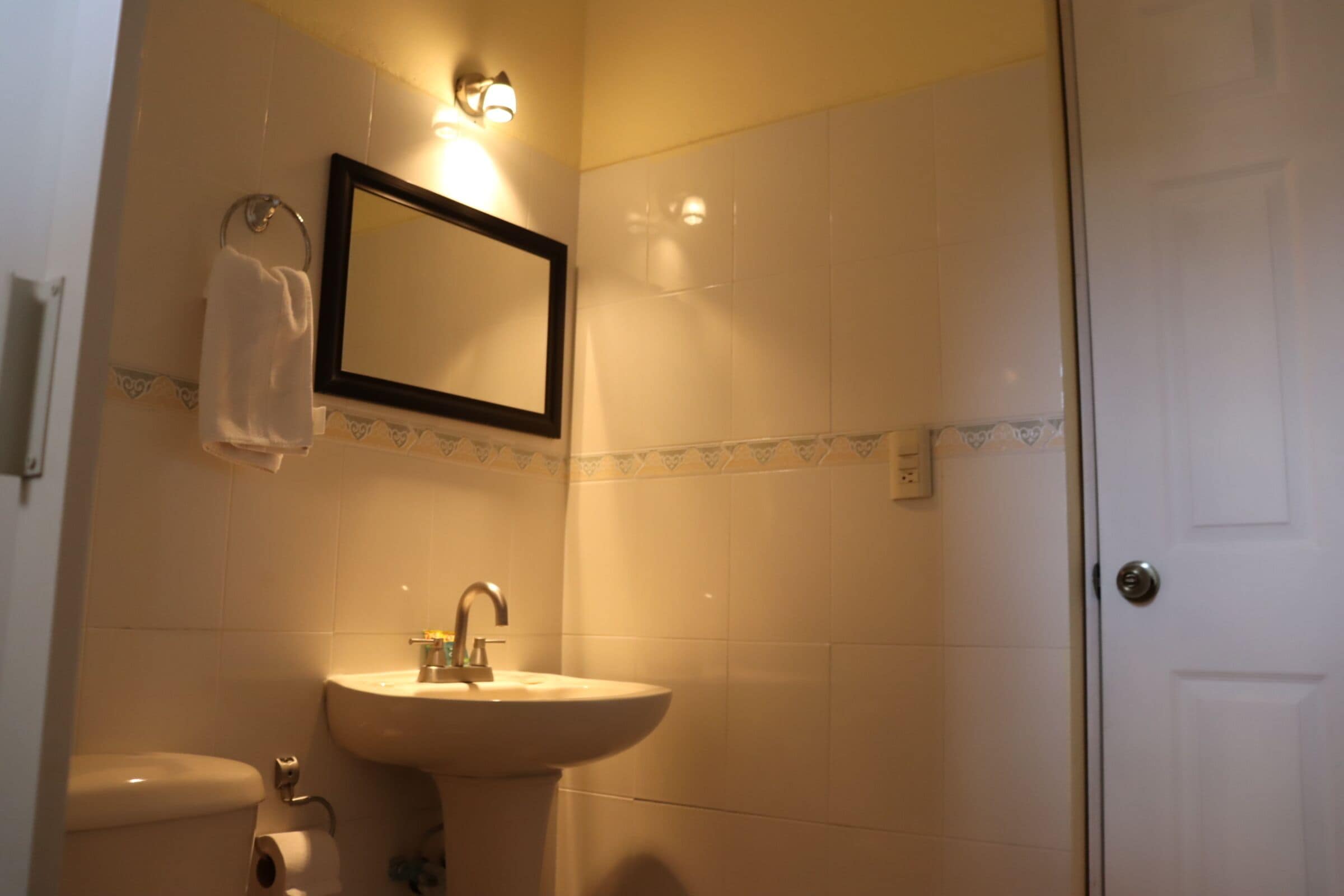 A bathroom with a sink, toilet, and a mirror.