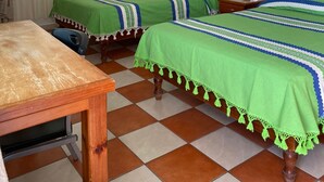 Ein Zimmer mit zwei Betten, einem Holztisch und einem karierten Boden.