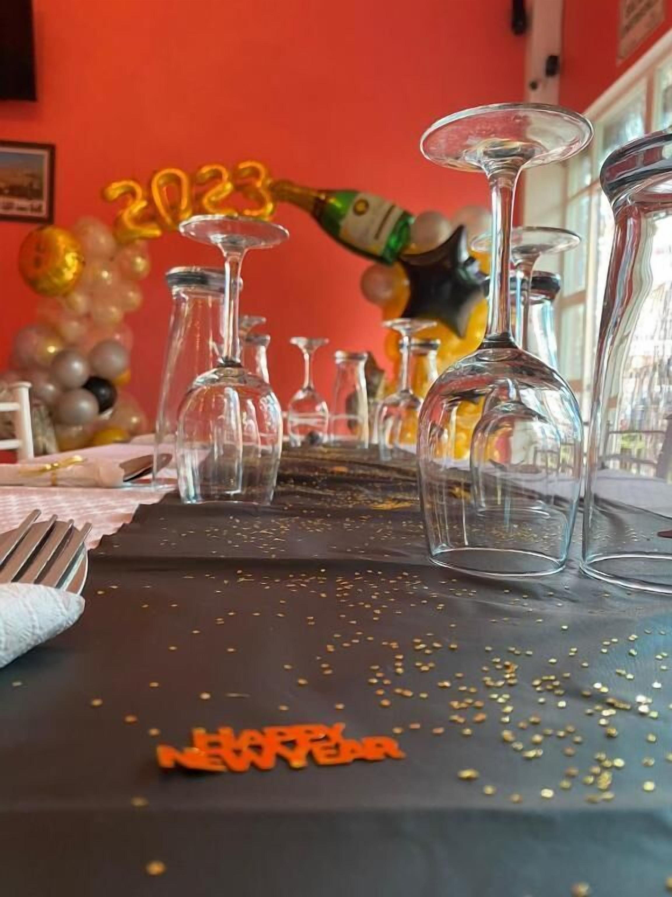 Une table avec des verres à vin vides et une bouteille de champagne, décorée avec les inscriptions « 2023 » et « Bonne année ».