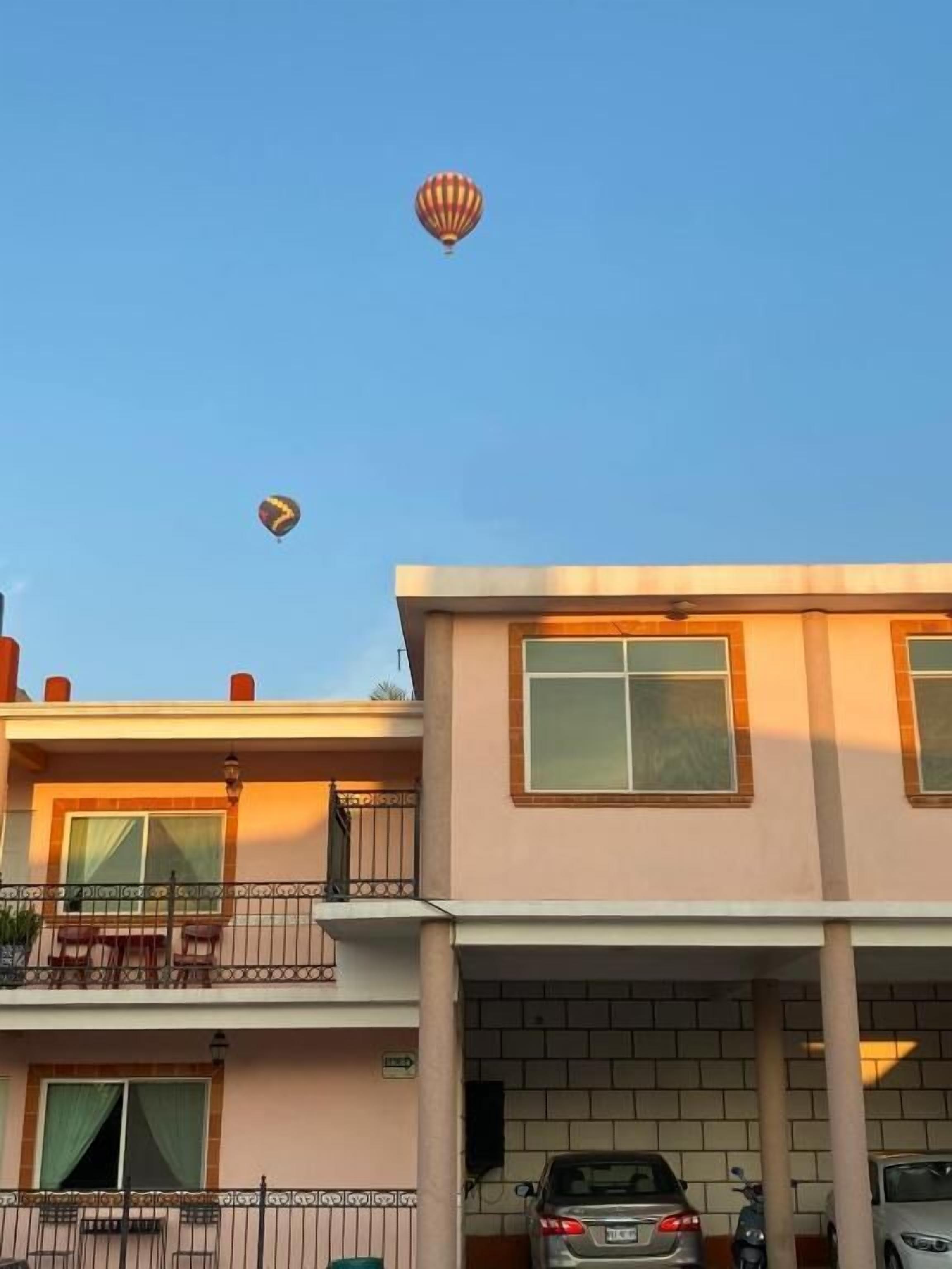 A two-story building with a balcony and a car parked in the driveway.
