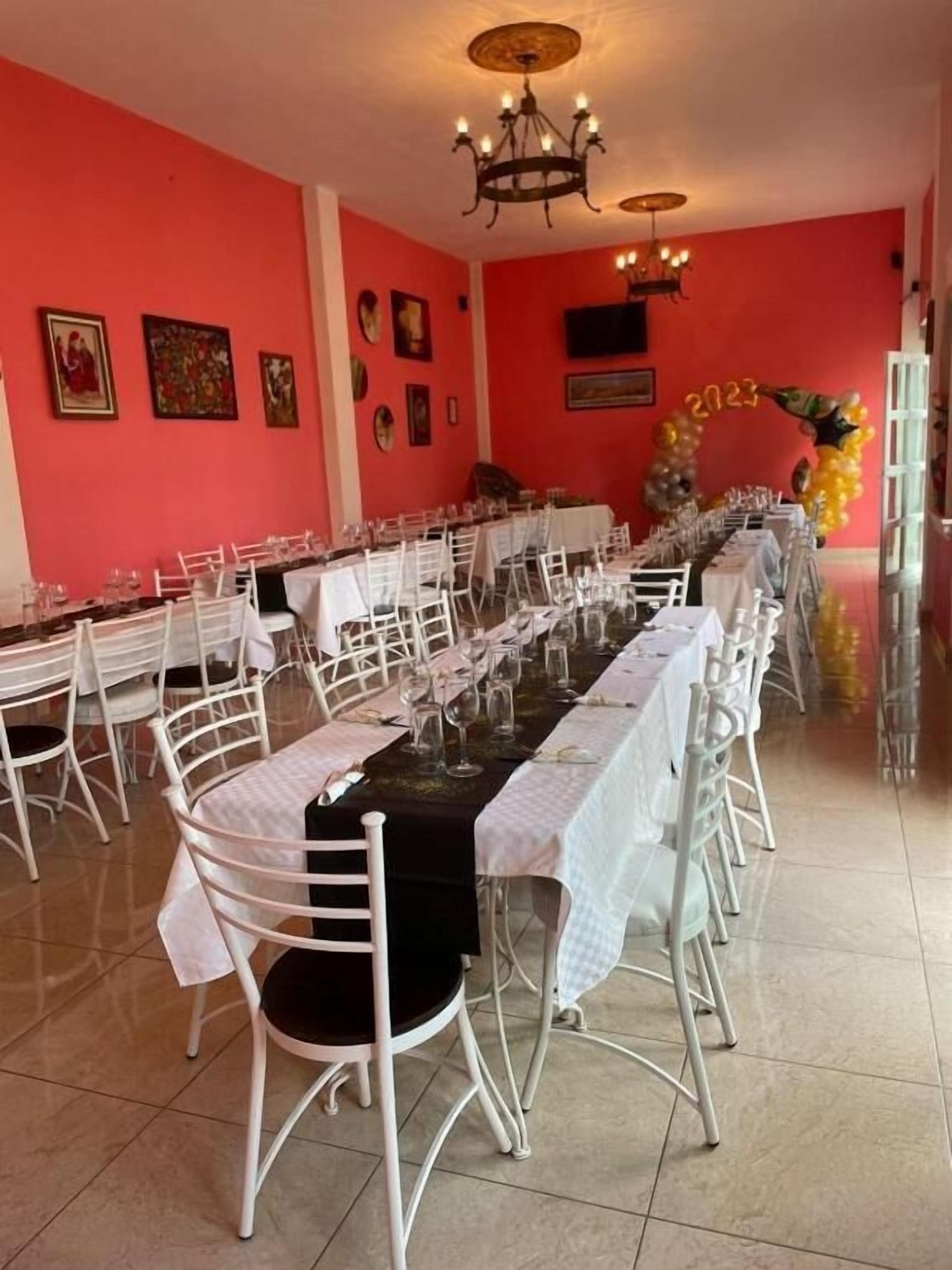 Un comedor con una larga mesa dispuesta para una comida, rodeada de sillas blancas.