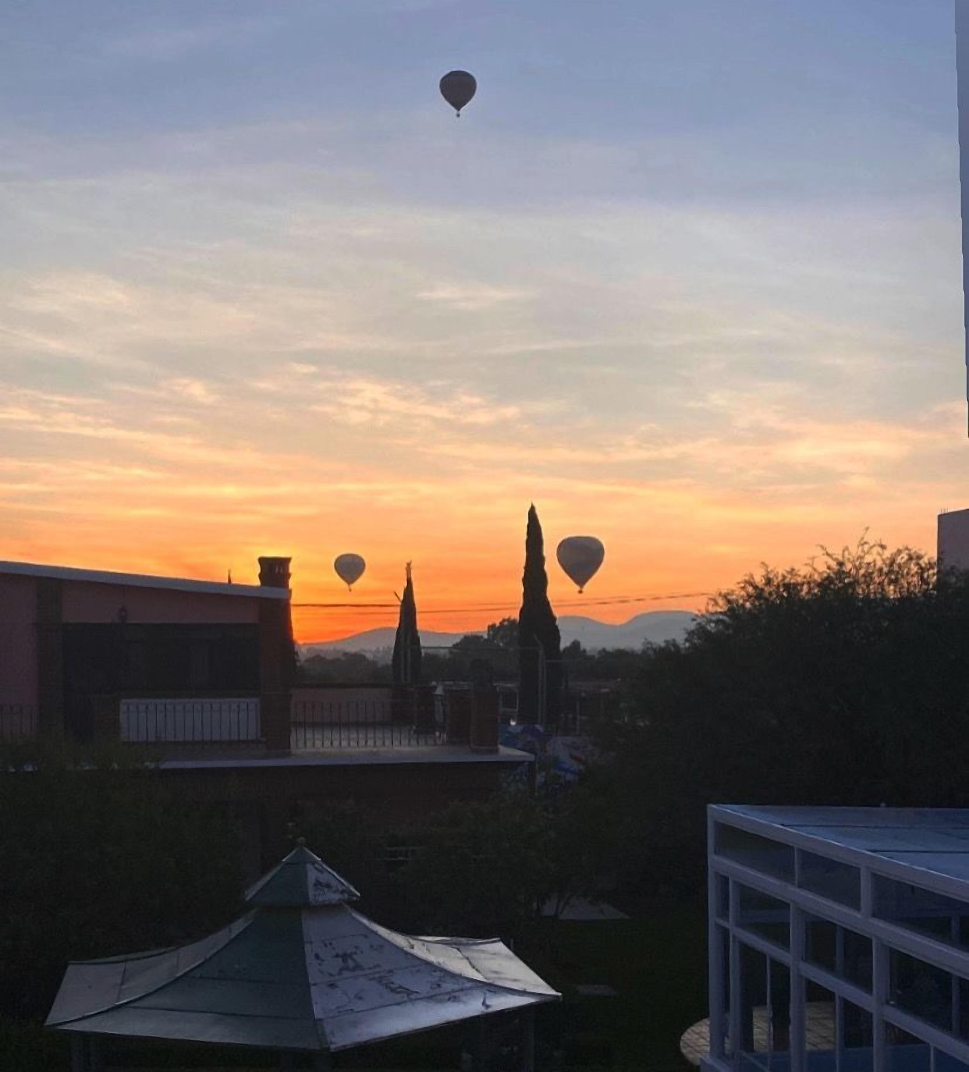 Un atardecer con globos aerostáticos en el cielo.