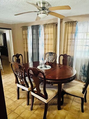 A dining area with a round table, six chairs, and a ceiling fan. - Cozy Caribbean Home Near Beaches (Christiansted)
