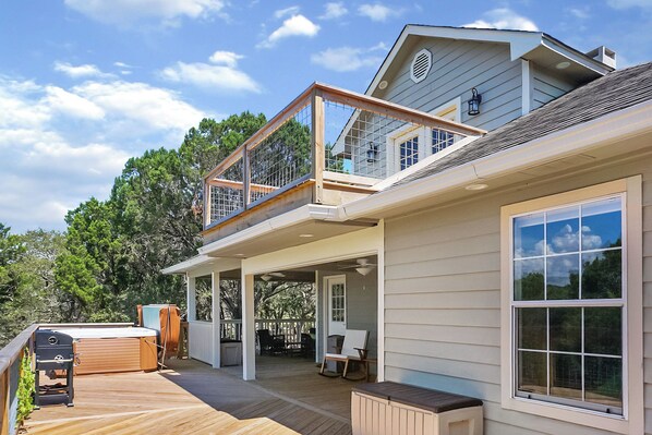 A house with a covered deck, a second-story balcony, and a large window.
