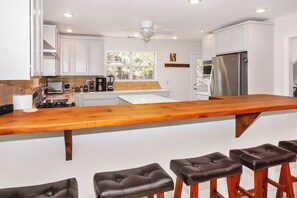 Una cocina moderna con armarios blancos, una isla de madera y un refrigerador de acero inoxidable.