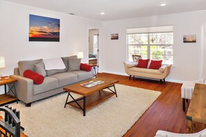 A living room with a sofa, a coffee table, and a window with a view. - Blue Spring Retreat I Hot tub, Families (Wimberley)