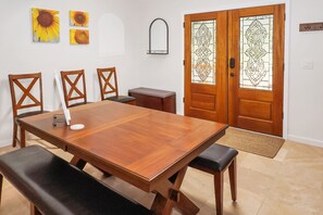 A dining area with a wooden table and four chairs, a small side table, and a decorative mirror on the wall. - Blue Spring Retreat I Hot tub, Families (Wimberley)