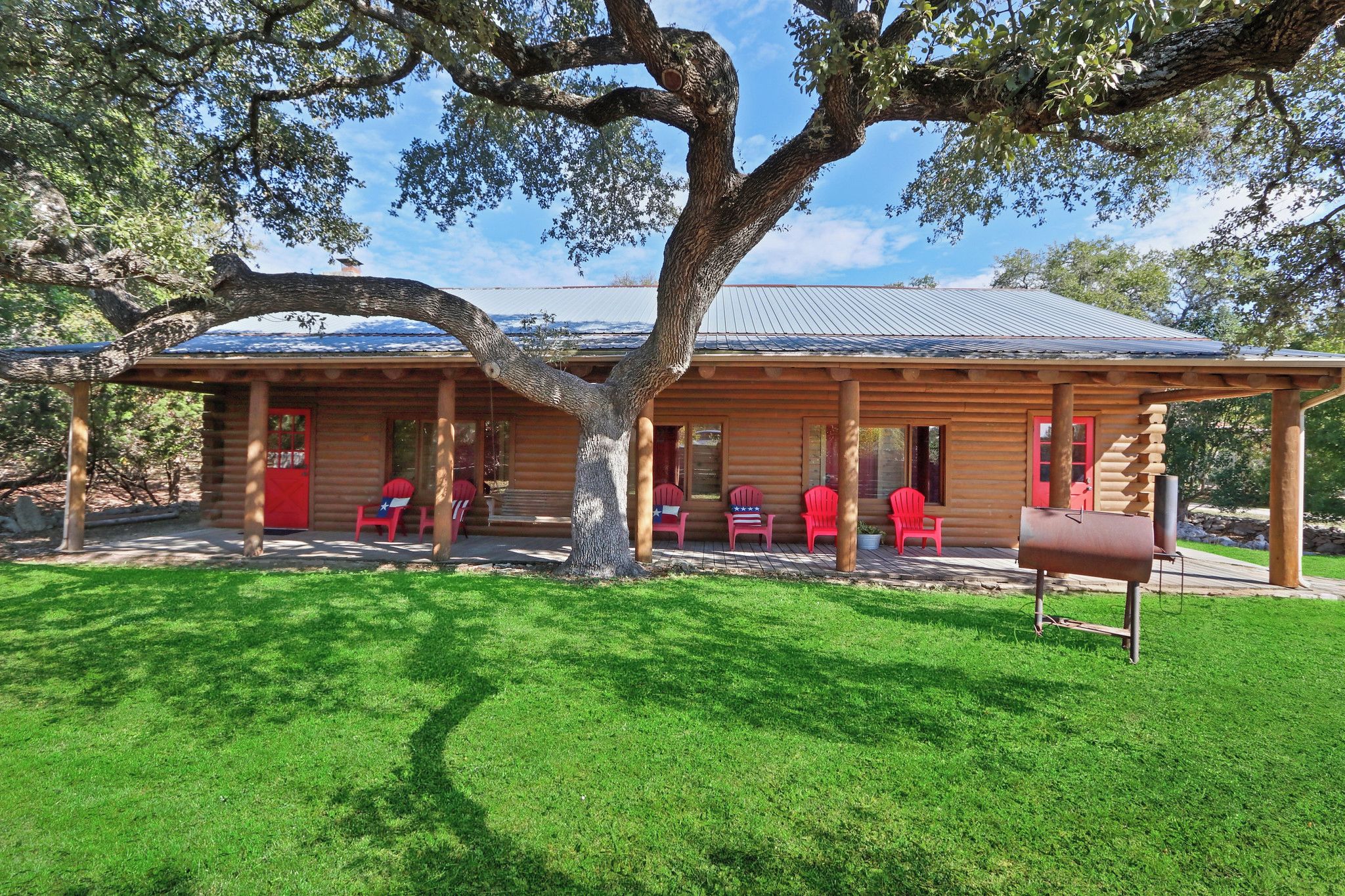 A log cabin with a porch, red chairs, and a mailbox.