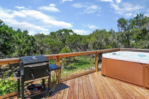 A wooden deck with a barbecue grill and a hot tub.