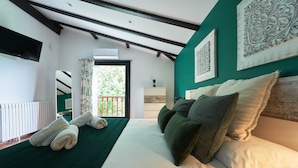 A bedroom with a large bed, a view to the outside, a radiator, and a ceiling with exposed beams.