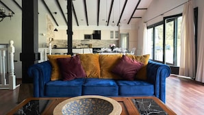 A modern living room with a blue sofa, a patterned coffee table, and a kitchen in the background.