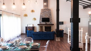 A dining area with a table set for four, a blue sofa, and a stone fireplace with a flat-screen TV.