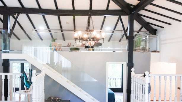 A spacious interior with a high ceiling, a staircase leading to an upper level, and a chandelier.